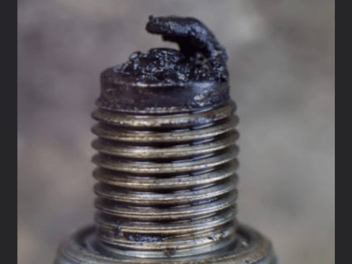 Car shaking due to engine misfire in Hemlock, MI. Closeup image of sparkplug with damage due to misfire at Hemlock Auto & Alignment.