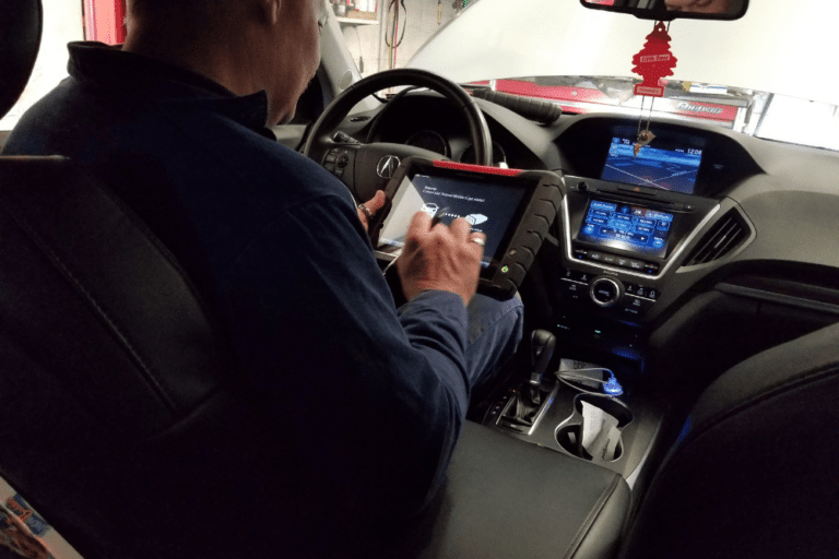 digital vehicle inspections, auto repair in Hemlock, MI at Hemlock Auto & Alignment. Image of a technician inside a modern vehicle using a diagnostic tool to analyze the car's electronic systems.